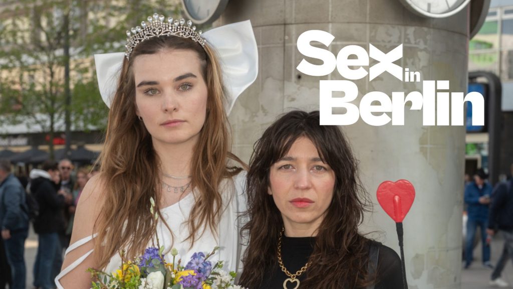 WEBSITE COVER-4 - Sex in Berlin Zwei Frauen stehen vor einer Uhr in Berlin, eine trägt ein Hochzeitskleid mit Krone, die andere hält einen Herzstab.