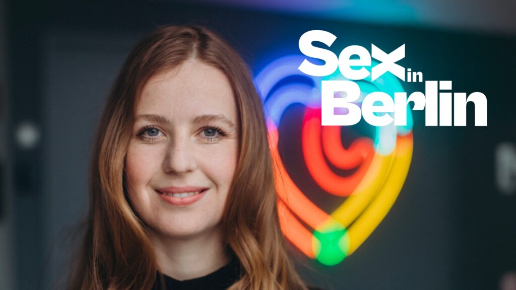 Smiling woman in front of a neon rainbow sign with the title 'Sex in Berlin' overlaid.